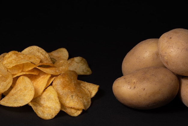 Chips and potato tubers on a black background