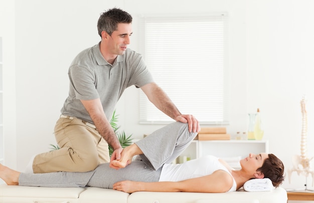 Chiropractor stretching a female customer's leg