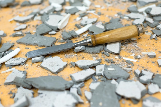 The chisel lies in the middle of pieces of cement and plaster Dirty littered workplace