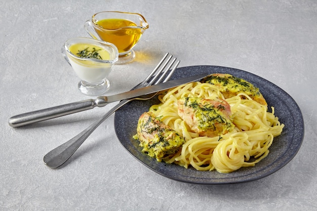 Chkemeruli on a dark plate with cutlery and gravy boats with oill and milk cream