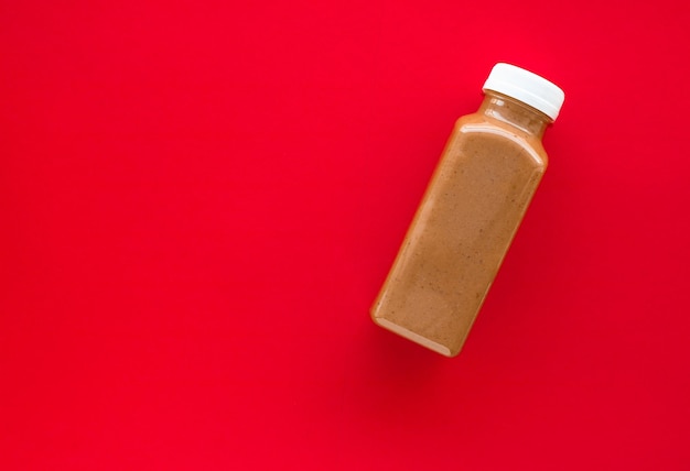 Chocolate banana smoothie bottle on red flatlay