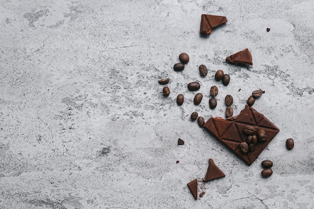 Chocolate bars and seeds on gray background with copy space. 