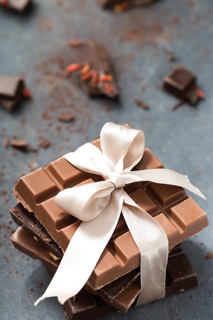 Chocolate bars with beige bow on a grey background