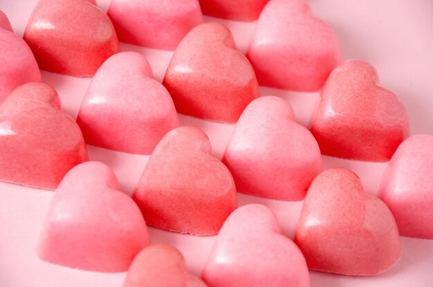 Chocolate bonbons in the shape of pink hearts Pink plain background