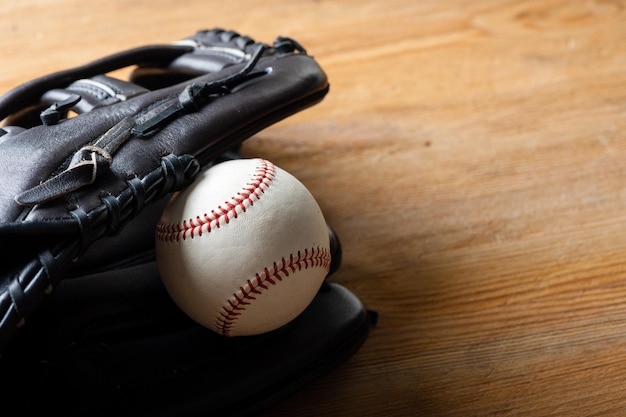 Chocolate brown baseball glove with baseball on wood board