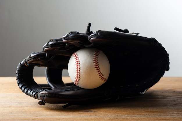 Chocolate brown baseball glove with baseball on wood board