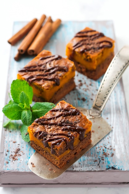 Chocolate brownie with a pumpkin on a light background. Selective focus.