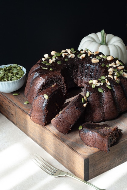 A chocolate bundt cake with a pumpkin on the side.