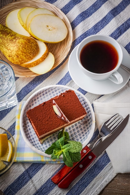 Chocolate cake, a cup of tea, lemon and slices of pear on background, horizontal. 