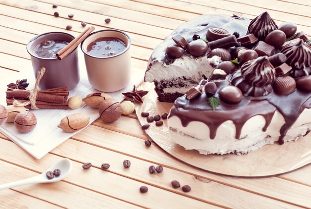 Chocolate cake decorated with chocolates with macadamia nuts and two cup of coffee