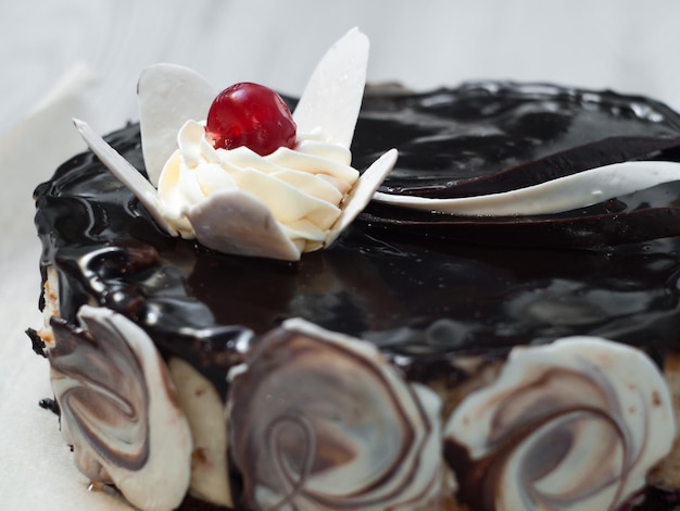 Chocolate cake decorated with a flower of white chocolate and cream