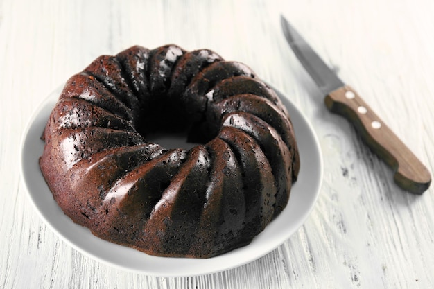 Chocolate cake on plate on white wooden background top view