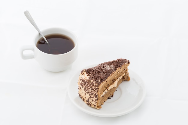 Photo chocolate cake slice with curl on white dish with hot drink