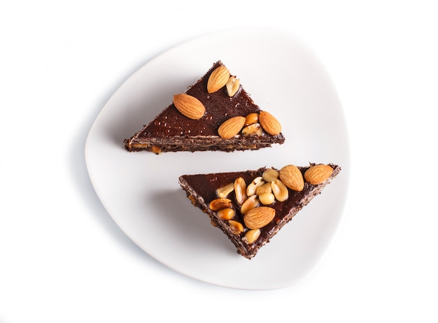 Chocolate cake with caramel, peanuts and almonds isolated on a white surface. 