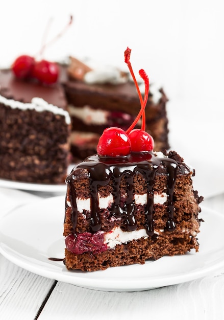 Chocolate cake with cherry on white wooden background