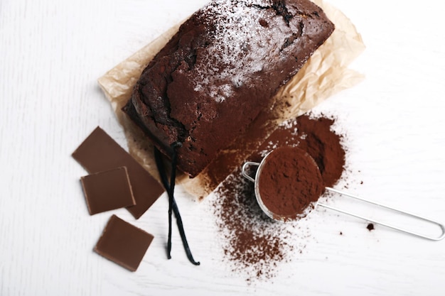 Chocolate cake with cocoa powder vanilla pods on white table