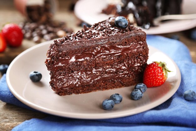 Chocolate cake with cream and fresh berries on plate on wooden background