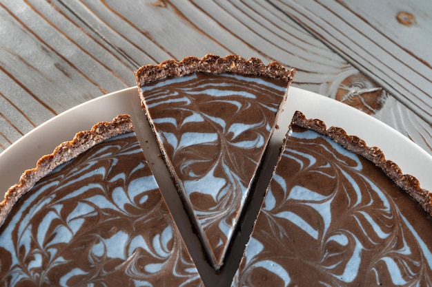 Photo chocolate cake with nuts laid on a plate beautifully cut piece wooden brushed background vegetarian