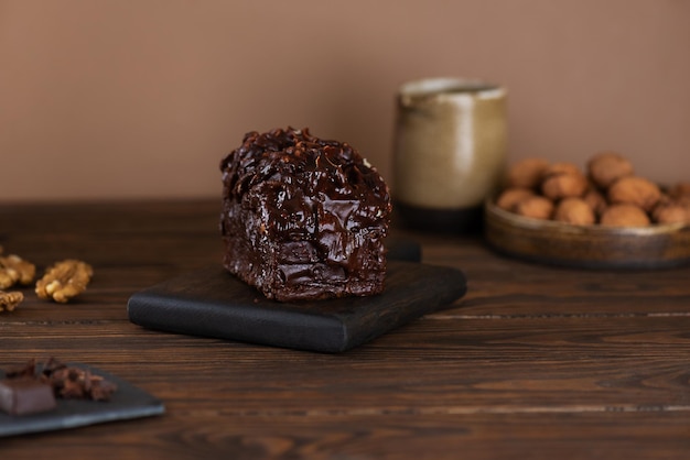 Chocolate cake with vanilla cream cheese and walnuts on a wooden table