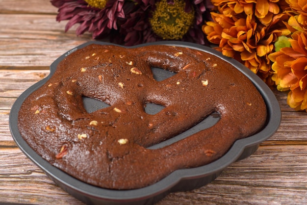 Chocolate cake with walnuts in the shape of a pumpkin lantern Freshly baked halloween cake close up