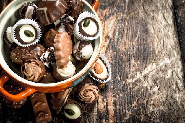 Chocolate candies in a bowl. On a wooden background.