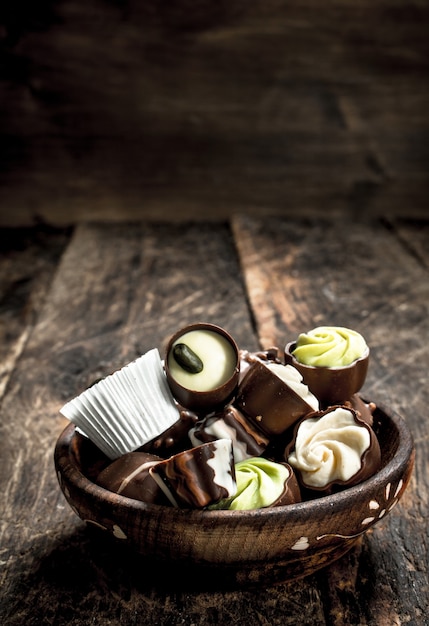 Chocolate candies in a bowl. On a wooden background.