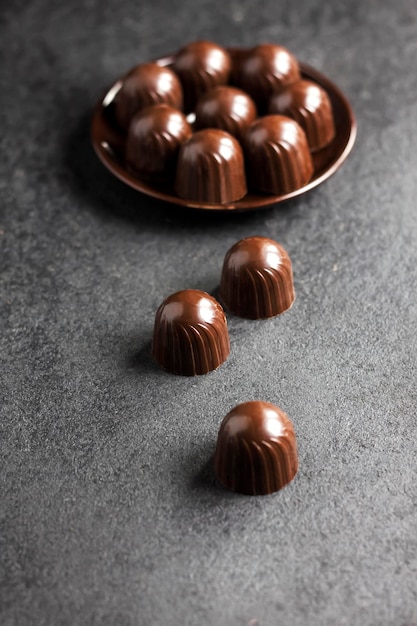 Chocolate candies on a plate on black background with copy space