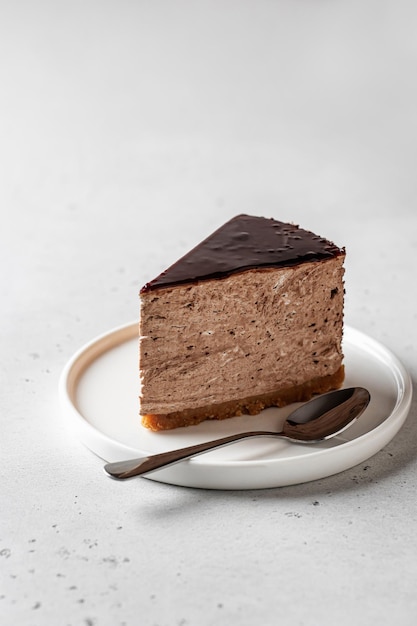 Chocolate cheesecake slice glazed on white textured background with text space