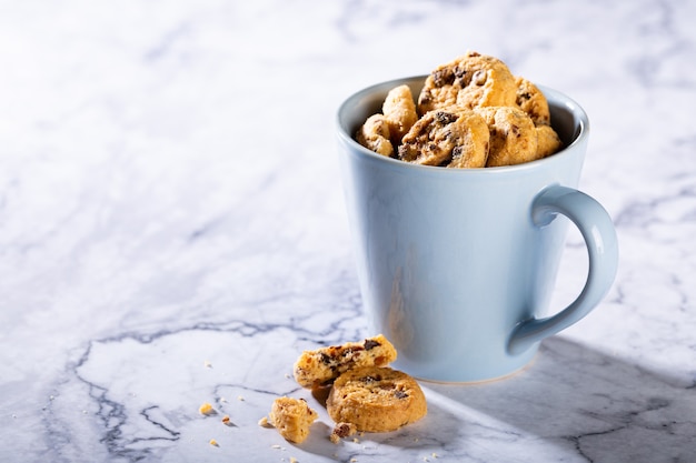 Chocolate chip cookies in blue cup on marble stone surface. Selective focus. Copy space