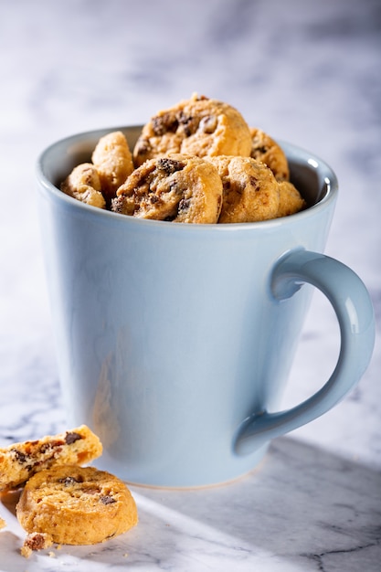 Chocolate chip cookies in blue cup on marble stone surface. Selective focus. Copy space