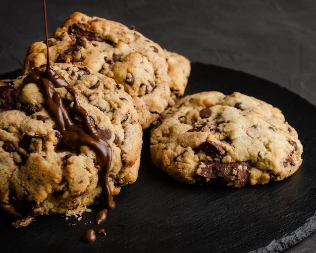 Chocolate chip cookies with chocolate syrup, on black background