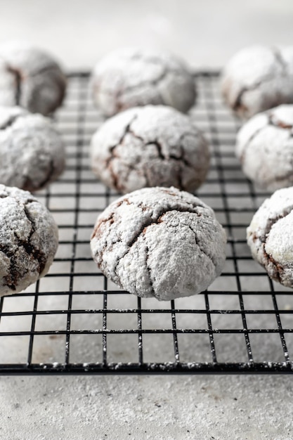 Chocolate chip cookies with cracks Metallic rack with fresh baked chocolate crinkle cookies in icing sugar on white textured background