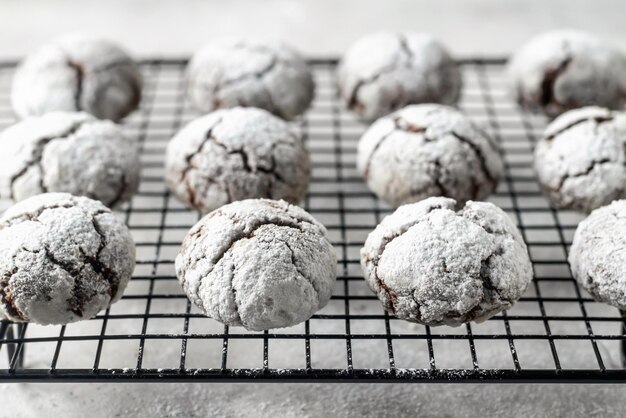 Chocolate chip cookies with cracks Metallic rack with fresh baked chocolate crinkle cookies in icing sugar on white textured background