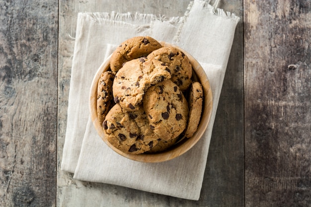 Chocolate chip cookies in wooden bowl on wooden table, top view