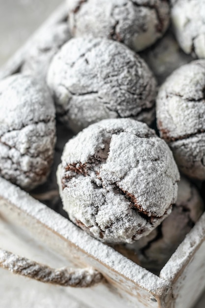 Chocolate chip cracked cookies close up Wooden rustic box with fresh baked chocolate crinkle cookies in icing sugar