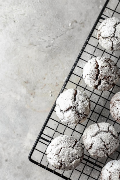 Chocolate chip cracked cookies Metallic rack with fresh baked chocolate crinkle cookies in icing sugar on gray textured background top view flat lay with space for text