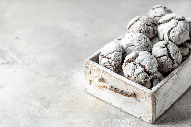 Chocolate chip cracked cookies Wooden rustic box with fresh baked chocolate crinkle cookies in icing sugar on gray textured background text space