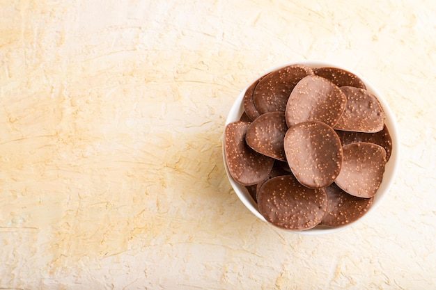 Chocolate chips on a beige concrete background top view copy space