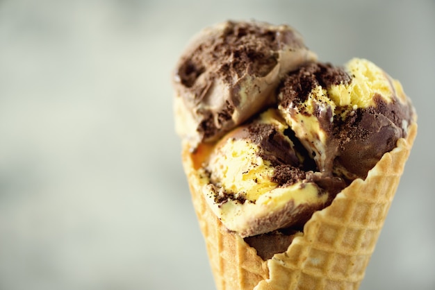 Chocolate and coffee ice cream in waffle cone with coffee beans on grey stone . Summer food concept, copy space. Healthy gluten free ice-cream