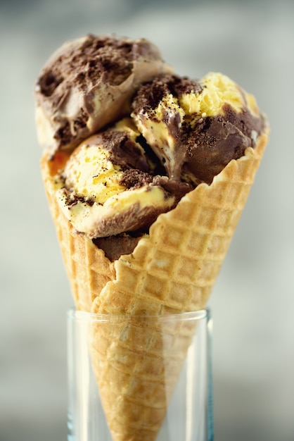 Photo chocolate and coffee ice cream in waffle cone with coffee beans on grey stone . summer food concept, copy space. healthy gluten free ice-cream