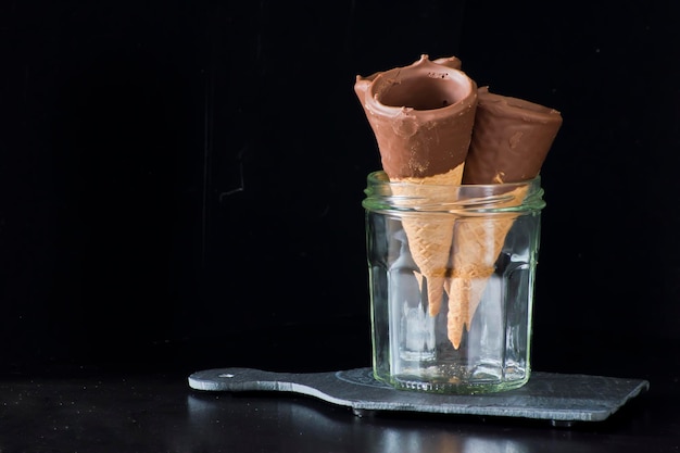 Chocolate cones in a glass jar. Dark background