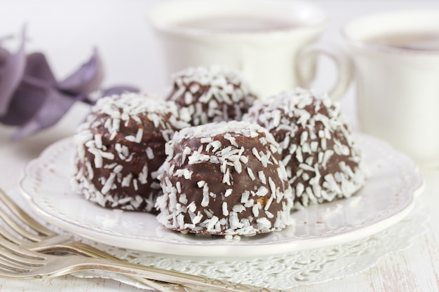 Chocolate cookies with coconut on white plate on white wooden table