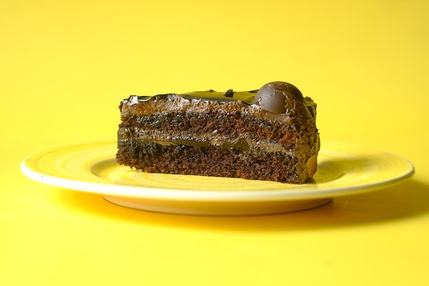 Chocolate and cream cake on a plate on yellow background