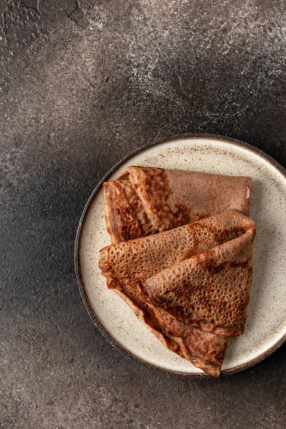 Chocolate Crepes folded on brown textured background rustic style top view flat lay