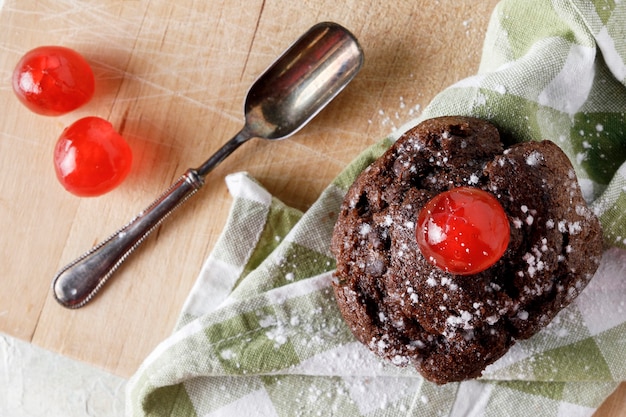 Chocolate cupcake with icing on napkin on wooden board and old spoon