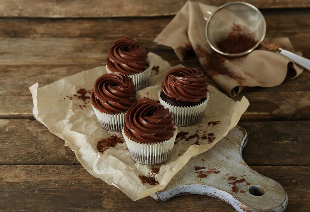 Photo chocolate cupcakes on baker paper over wooden background