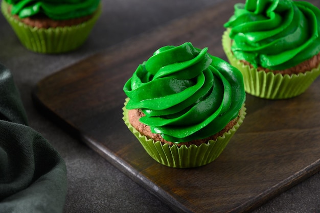 Chocolate cupcakes with green whipped cream and chocolate sprinkles