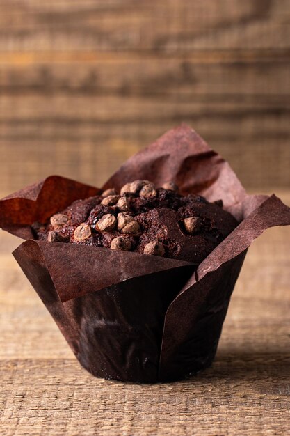 Photo chocolate dark muffin with chocolate chips and drops on a wooden table