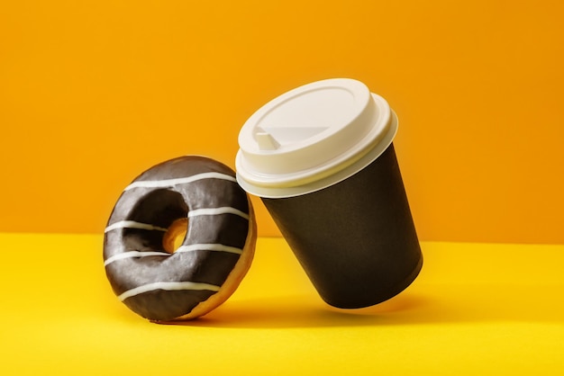 Chocolate donut and a glass of coffee on a bright background of orange and yellow