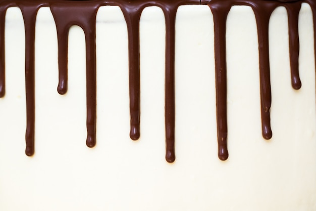 Chocolate drips on the background of white cream